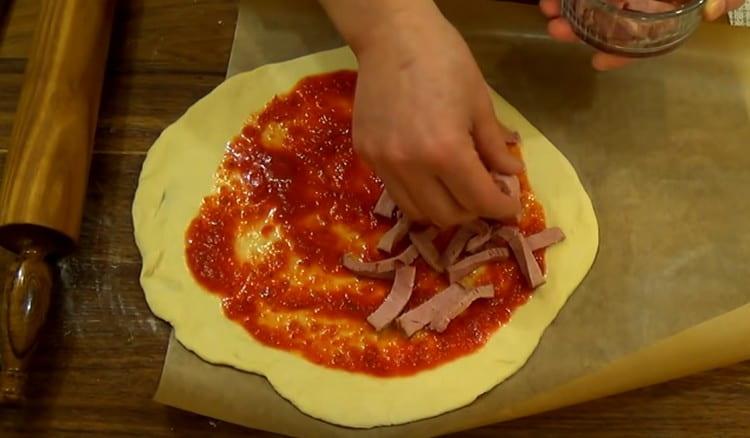 A metà dell'impasto spalmato di salsa, mettere la salsiccia a fette.