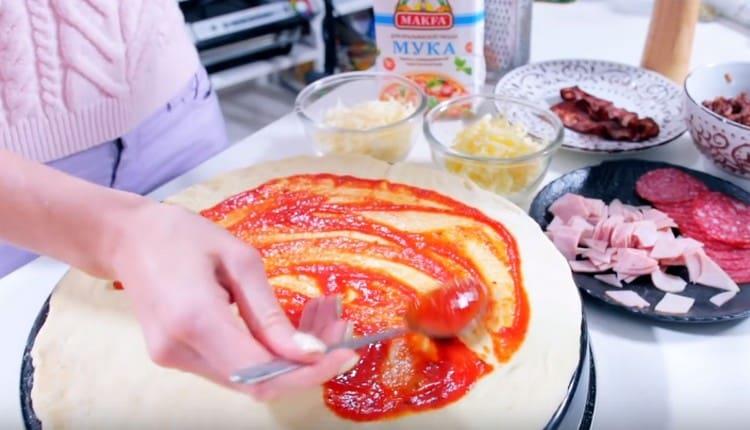 Ungere l'impasto con la salsa di pomodoro.