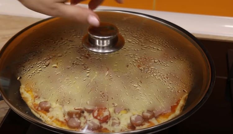 Mettiamo la padella con la pizza sul fuoco, copriamo con un coperchio.