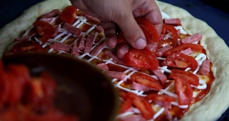 Spalmiamo le fette di pomodoro sopra la salsiccia.