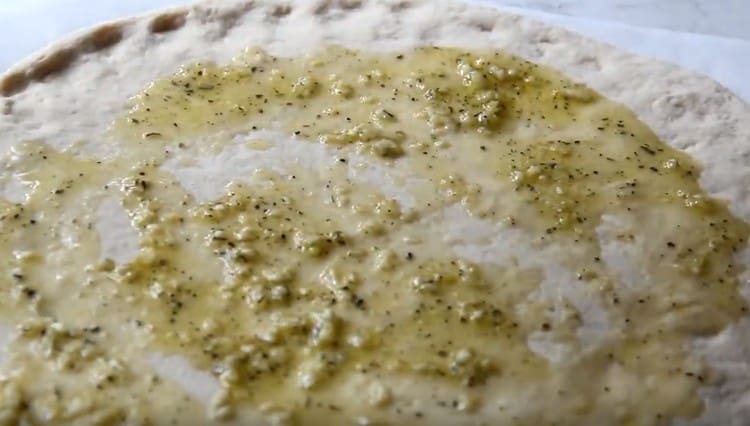 Per prima cosa, ungere la base della pizza con olio all'aglio.