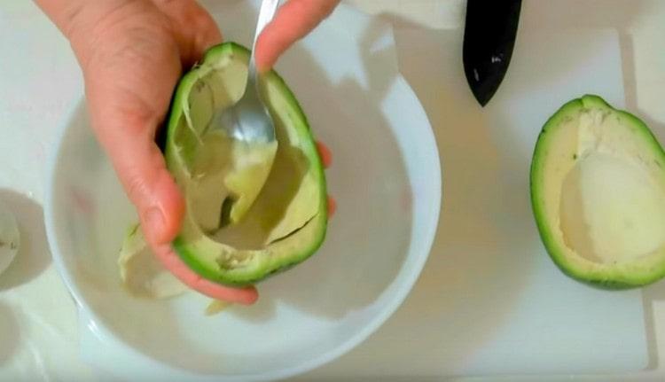 Cucchia delicatamente la polpa di avocado e trasferiscila in una ciotola.