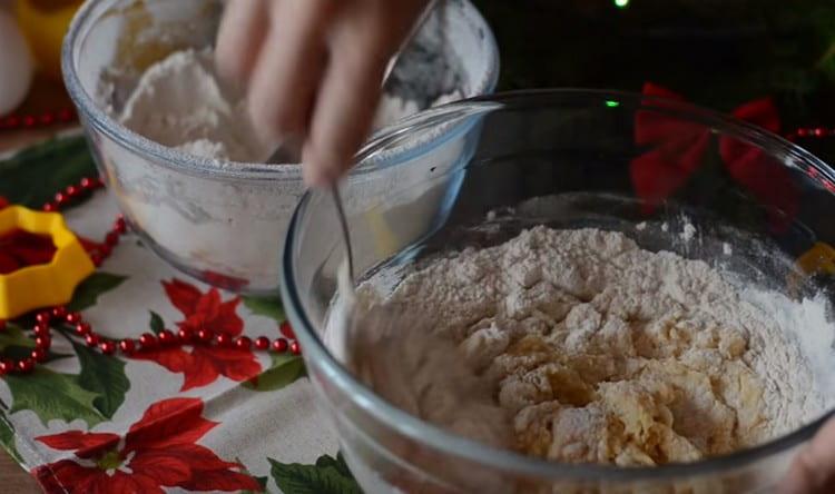 Aggiungi la farina in parti, impasta l'impasto.