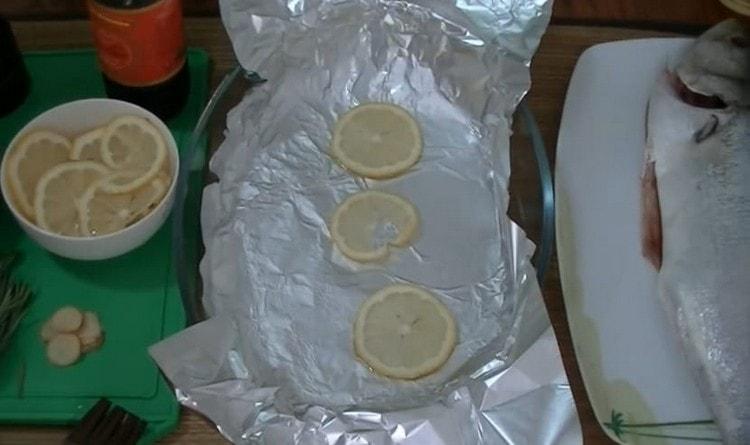 Takpan ang baking dish na may foil, grasa na may langis ng gulay at kumalat ng ilang hiwa ng lemon.