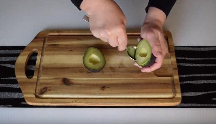 Con un cucchiaino, separa la carne dell'avocado dalla buccia.