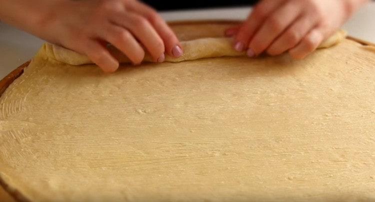 Trasformiamo con cura i tre strati di pasta incollati insieme in un rotolo stretto.