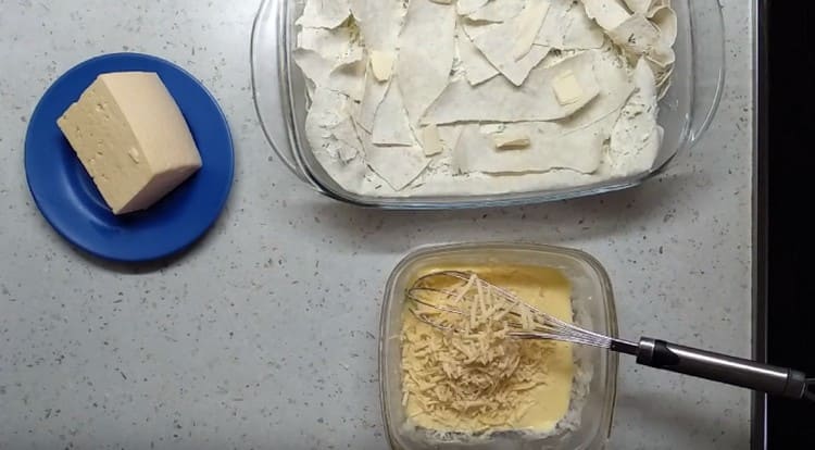 Preparando per il ripieno di torta dell'uovo. panna acida e formaggio grattugiato.