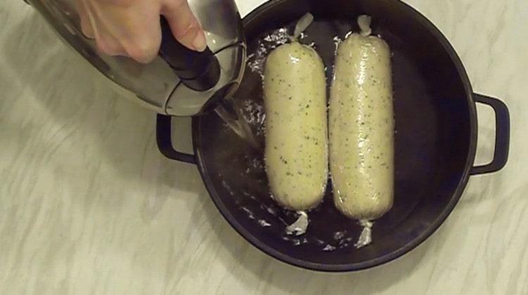 Mettiamo le salsicce con il soufflé nella padella. riempire d'acqua.