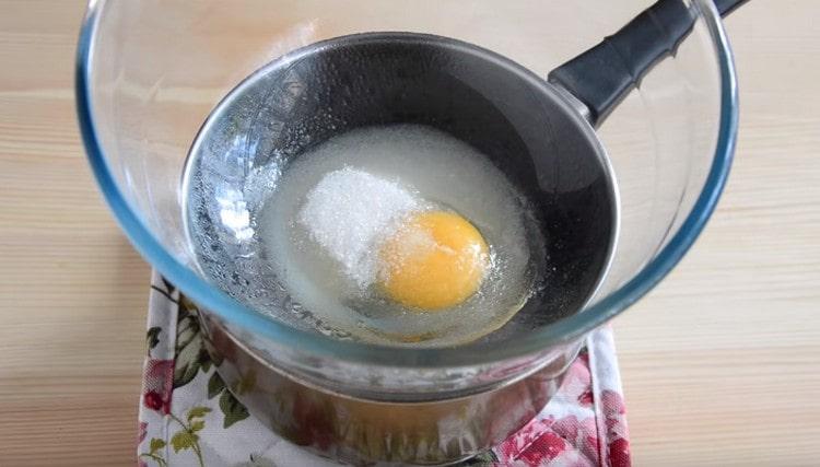 Mettiamo una ciotola a bagnomaria, versiamo lo zucchero e sbattiamo l'uovo.