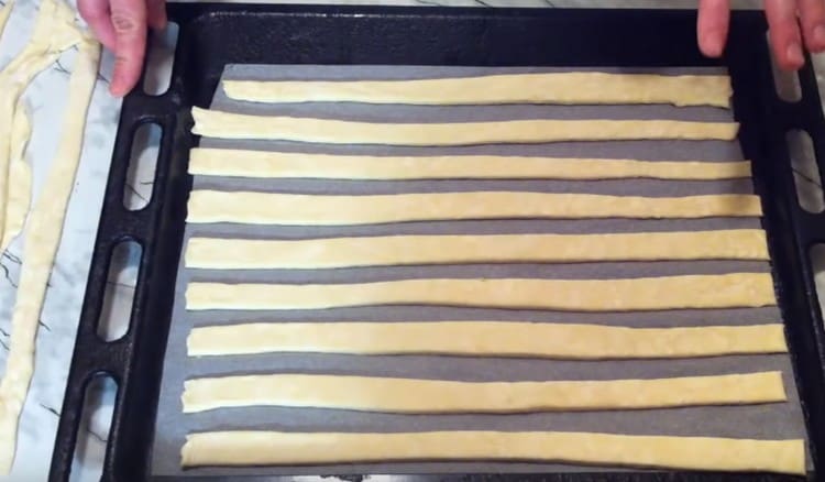 Distribuiamo strisce di pasta su una teglia coperta di pergamena.