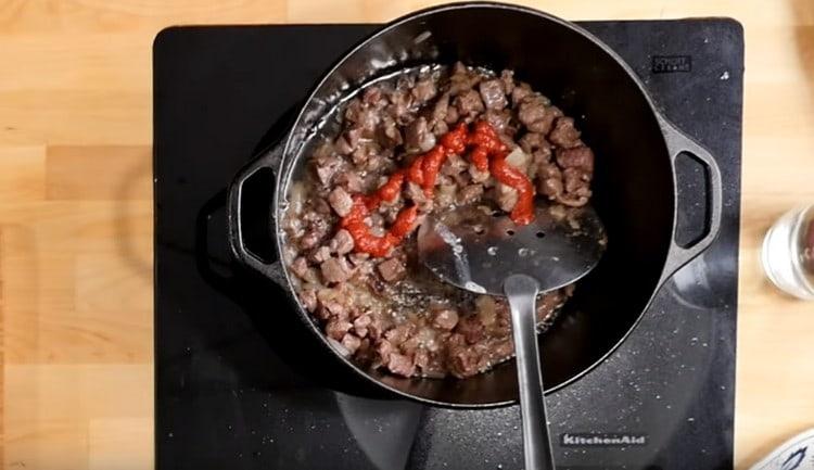 Aggiungi il concentrato di pomodoro alla carne con le cipolle.