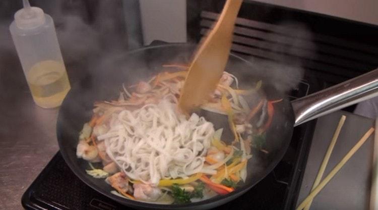 Distribuiamo i noodles nella padella al pollo e alle verdure, mescoliamo.