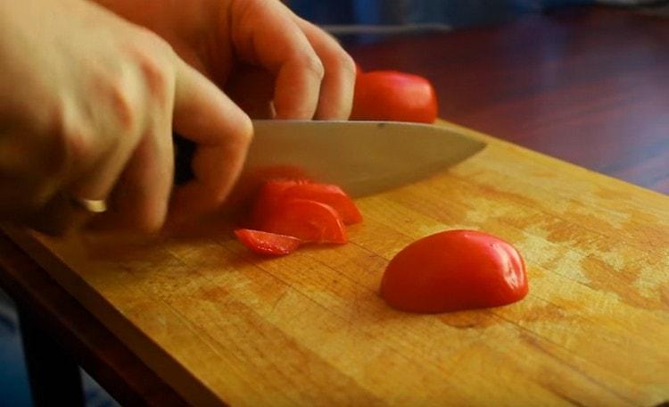 Tagliamo i pomodori in semicerchi sottili.