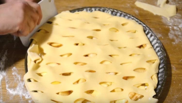 Copriamo la base della torta con lo strato di pasta ottenuto, ruotiamo i bordi verso l'interno, tagliamo l'eccesso.