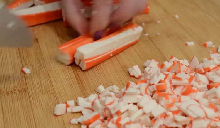 Per preparare le cotolette con bastoncini di granchio, tagliare tutti gli ingredienti per la carne macinata.