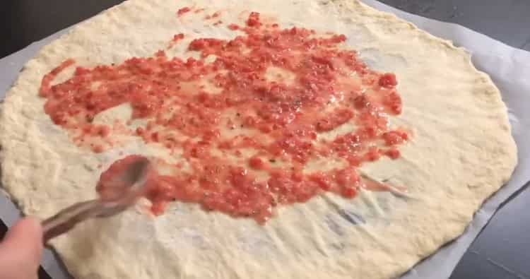 Per preparare una pizza napoletana, metti la salsa sull'impasto