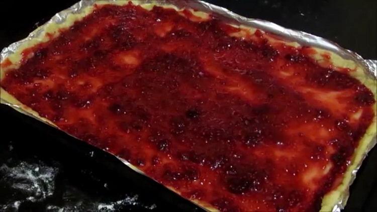 Per fare i biscotti di pasta frolla con la marmellata, mettere l'impasto su una teglia e la marmellata su una pastella