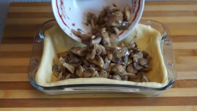 Per fare una torta con funghi nel forno, mettere il ripieno sull'impasto