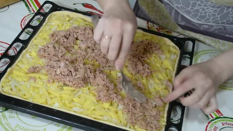 Per preparare una torta con pesce e patate, metti tutti gli ingredienti sull'impasto