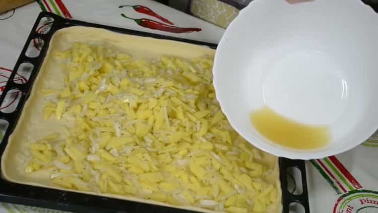 Per preparare una torta con pesce e patate, metti il ​​ripieno sull'impasto