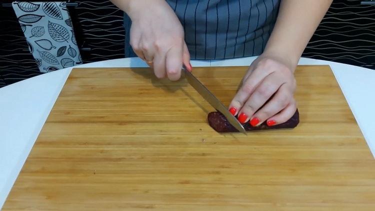 Per fare la pizza a casa, tagliare la salsiccia