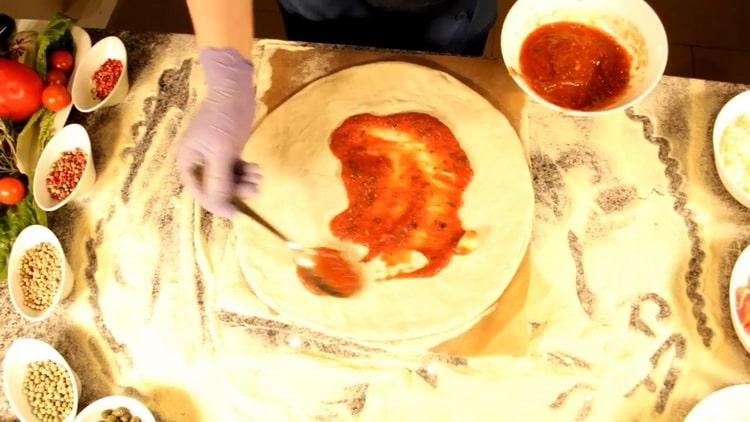 Per fare la pizza alla carbonara, ungere l'impasto con la salsa