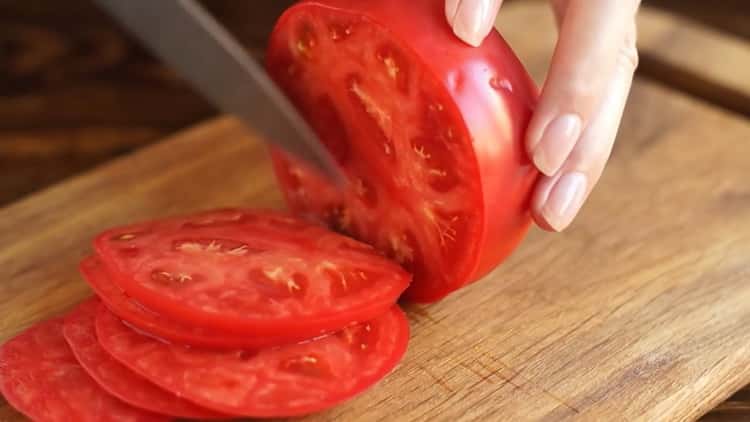 Per preparare la pizza alla margarita, tagliare il pomodoro