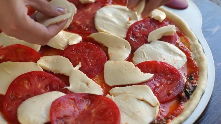 Per preparare la pizza alla margarita, metti il ​​ripieno sull'impasto