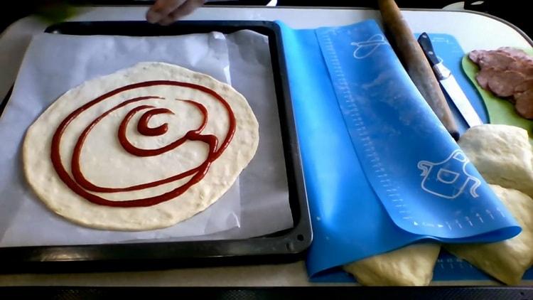 Per preparare la pizza al kefir in forno, ungere l'impasto con ketchup