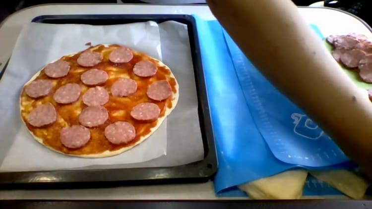 Per cuocere la pizza sul kefir nel forno, tagliare la salsiccia