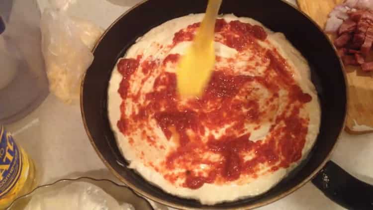 Per fare la pizza, ungere l'impasto con concentrato di pomodoro