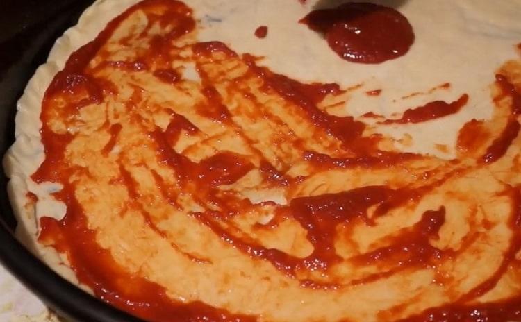 Per fare la pizza con salsiccia e formaggio, metti la salsa sull'impasto