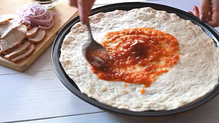 Per fare la pizza con il pollo, ungere il modulo con la salsa