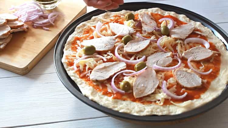 Per fare la pizza con il pollo, metti il ​​ripieno sull'impasto