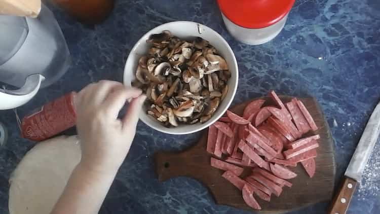 Per fare la pizza con sottaceti, tagliare salsicce e funghi