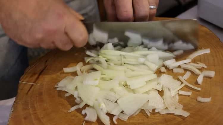 Per cuocere il pilaf di maiale in una padella, tritare la cipolla