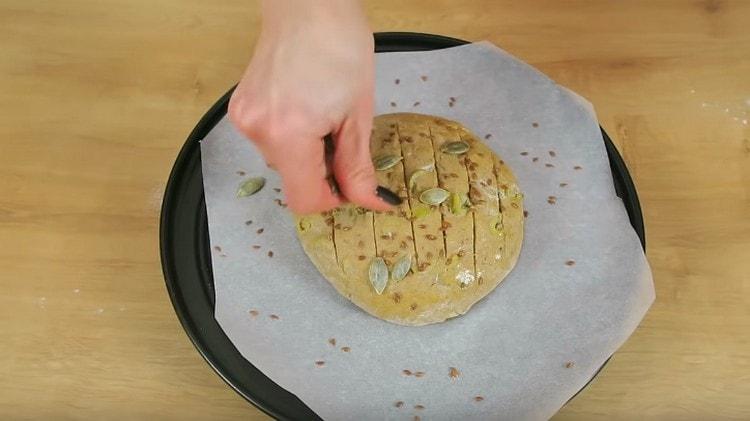 Ungi una pagnotta di olio d'oliva e cospargi di semi di lino e semi di zucca.