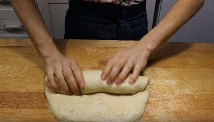 Distribuiamo l'impasto su una superficie di lavoro cosparsa di farina, arrotoliamolo un po 'in un rettangolo e ruotandolo con un rotolo.