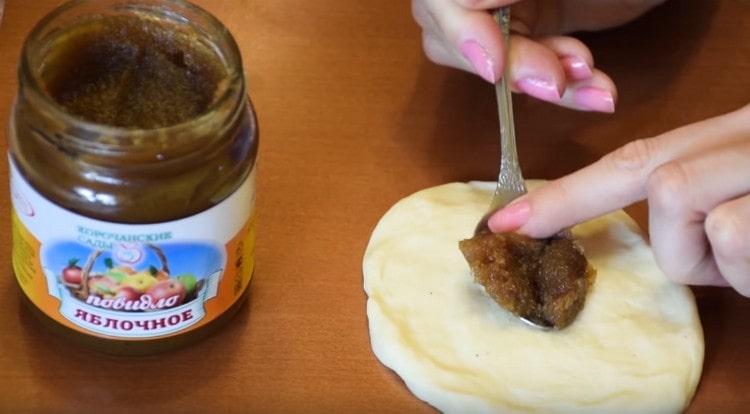 Impastare le palline di pasta nelle torte e distribuire la marmellata al centro di ciascuna di esse.