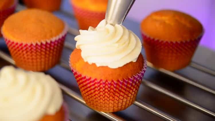 Per preparare i cupcake a casa, lascia cadere la panna su un cupcake