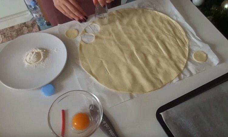 Con un tagliabiscotti o un bicchiere, tagliamo i cerchi dallo strato di pasta.