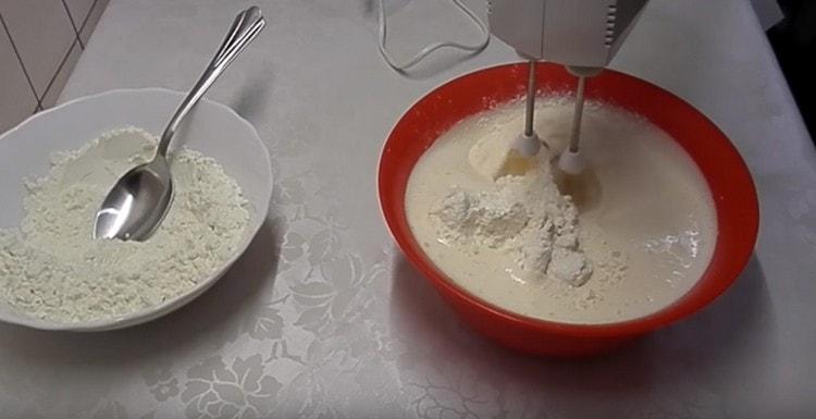 Aggiungi la farina in parti, ogni volta mescola l'impasto con un mixer.