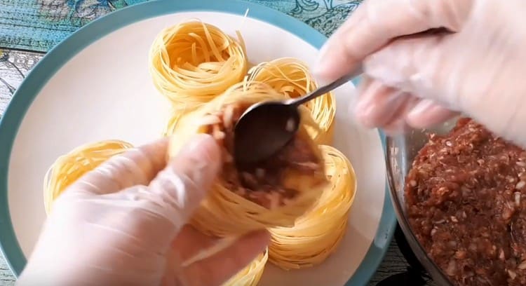 Riempiamo i nidi di pasta secca con carne macinata.