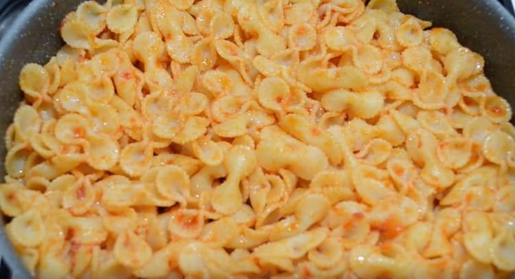 Trasferiamo la pasta nella padella e mescoliamo con il concentrato di pomodoro.