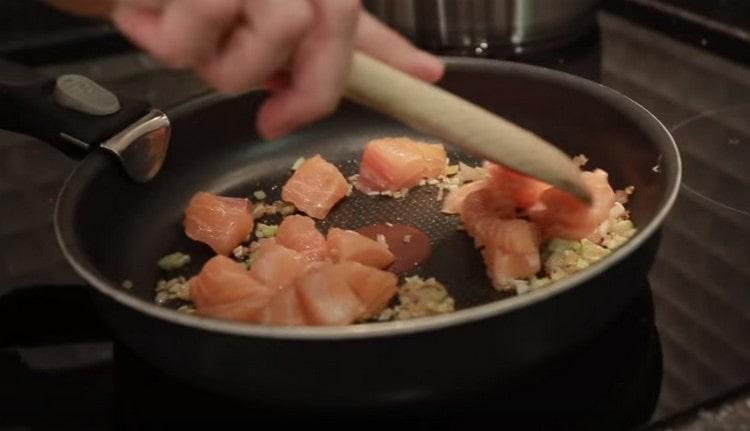 Insieme all'aglio tritato, spalmare il salmone in una padella sulla cipolla.