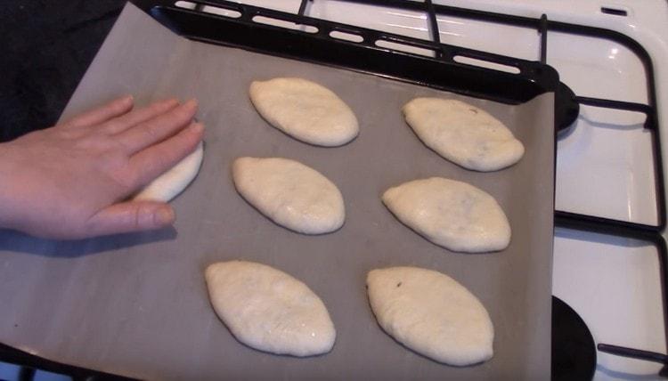 Metti le torte su una teglia coperta di pergamena e premi delicatamente verso il basso con la mano.