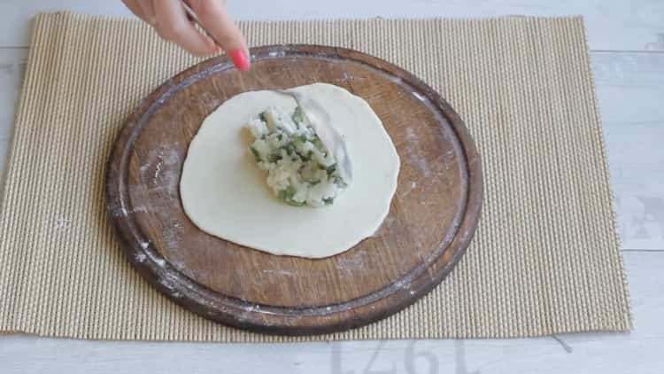 Per fare torte con riso e uova, metti il ​​ripieno sull'impasto.