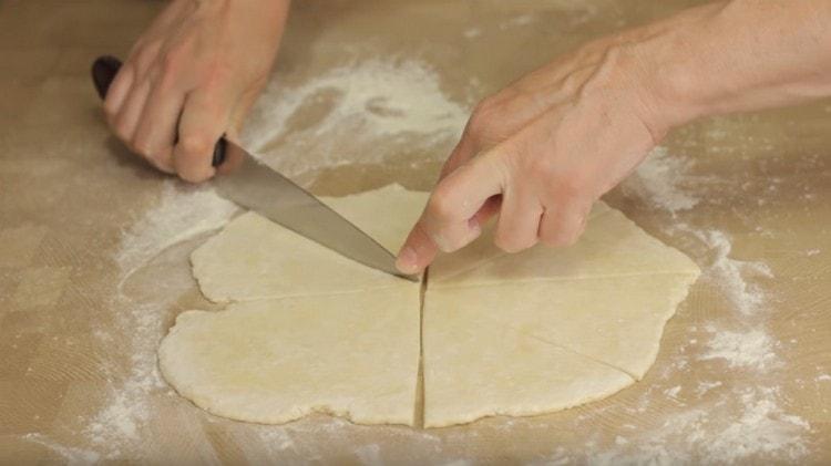 Dopo aver tagliato metà dell'impasto, arrotoliamo questo pezzo in un cerchio, che tagliamo a triangoli.