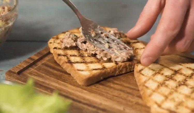 Distribuire una massa di tonno sul pane tostato.