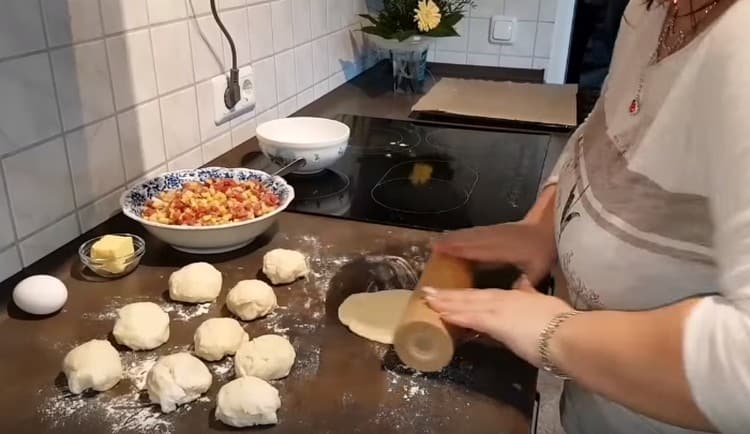 Formiamo palline porzionate dall'impasto e le arrotoliamo con un mattarello.